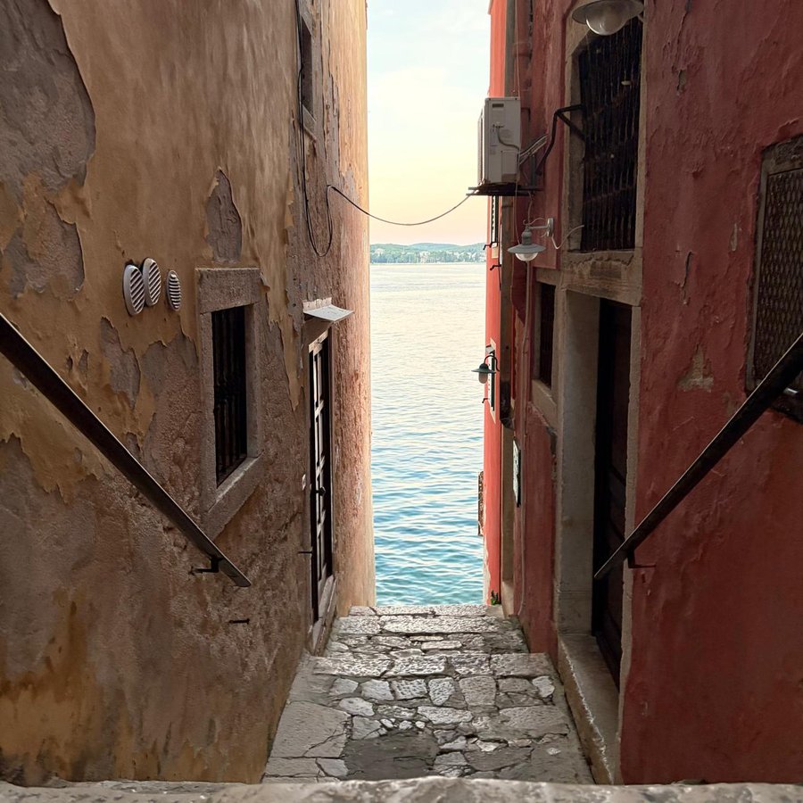 A narrow, weathered street of ochre and red houses stepping down to the sea in Rovinj